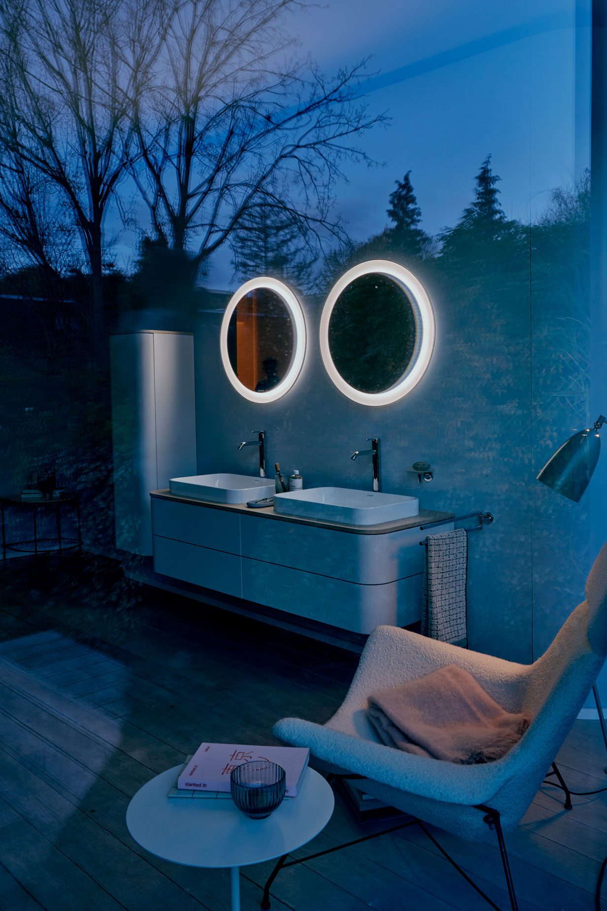 Dunkles Badezimmer mit zwei runden und beleuchteten Spiegeln