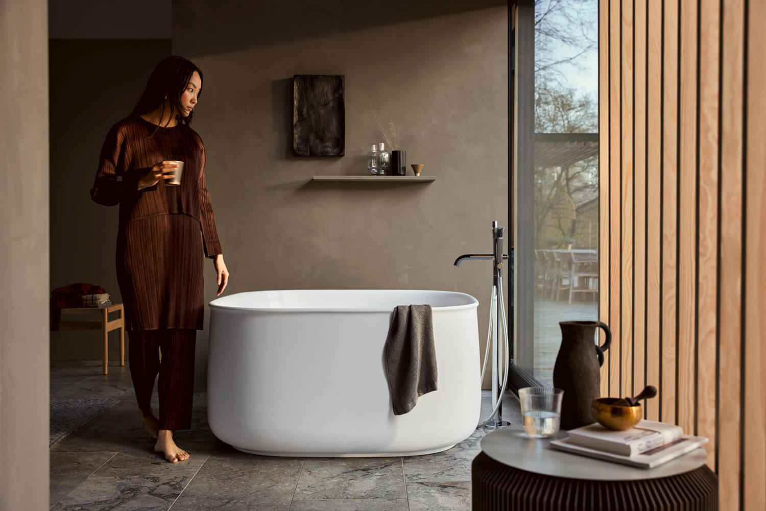 Woman with tea in front of free standing zencha bathtub
